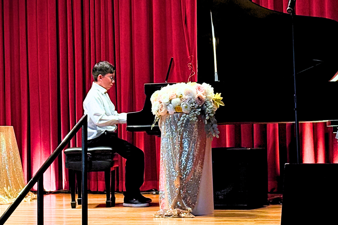 Young pianist, age 10, performing on a grand piano on stage at the RC Piano Lessons recital.